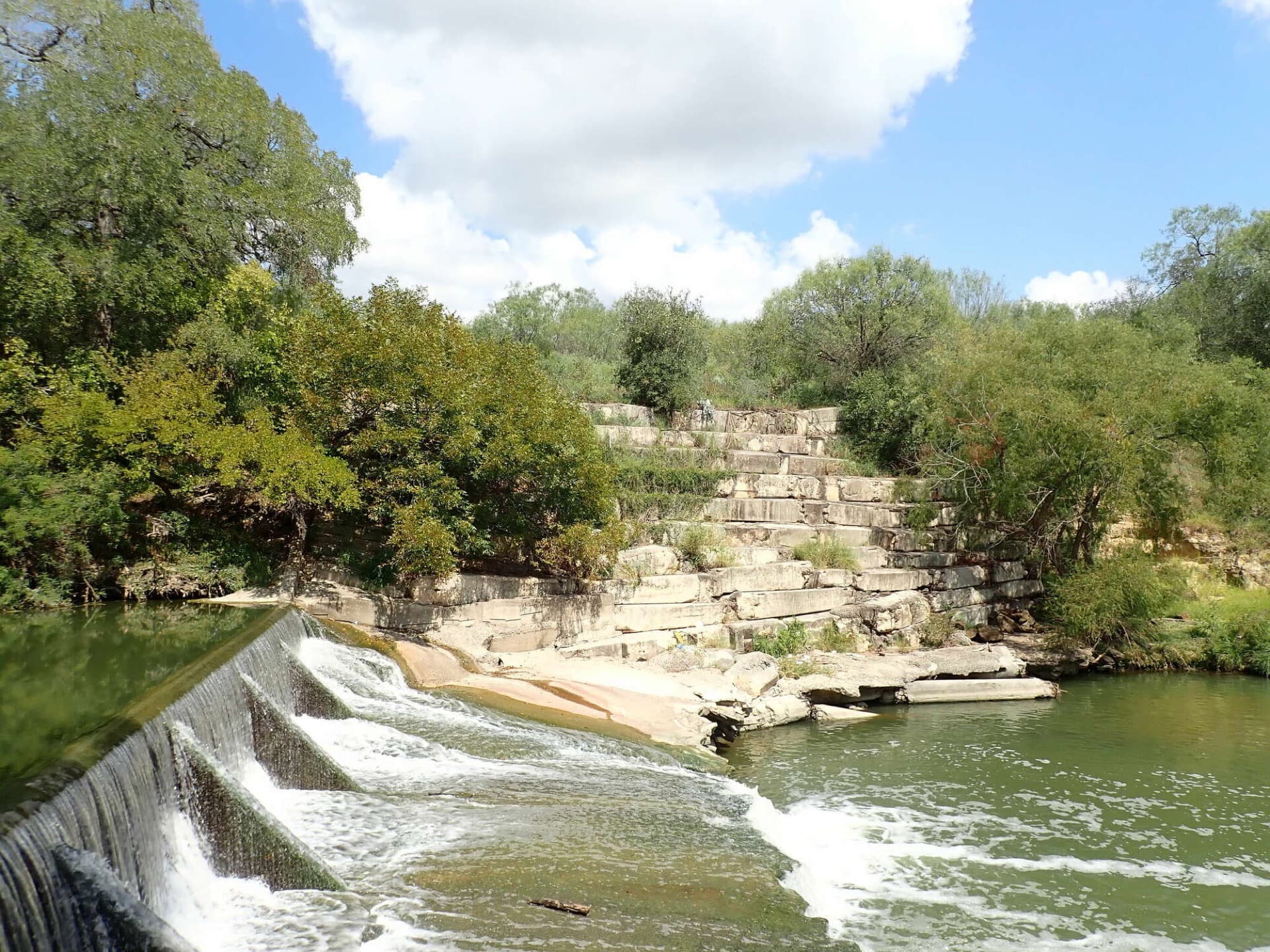 A spillway discharging over its stepped weir into the channel below.