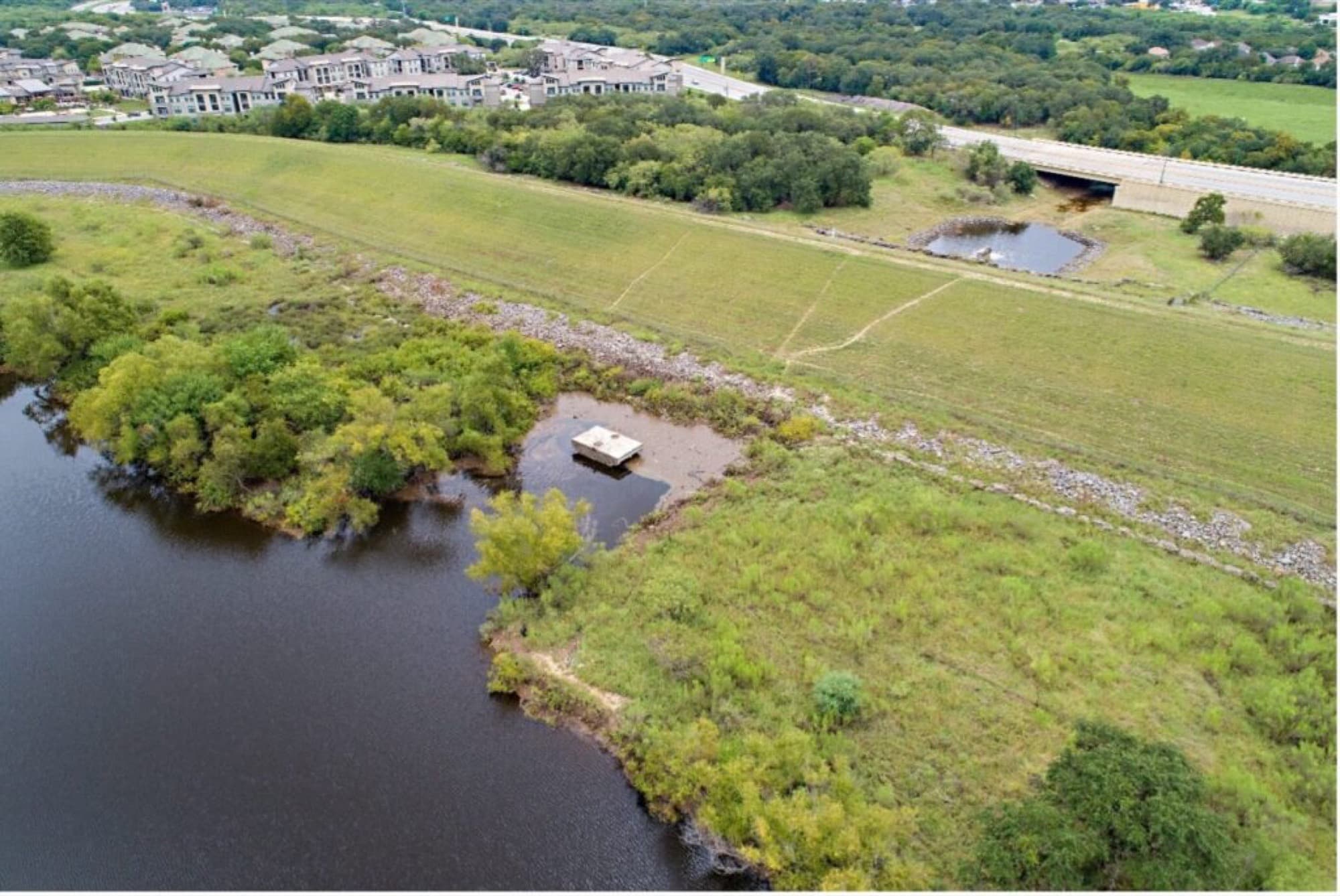Aerial view of a flood control embankment with an apartment development built immediately upslope of it.